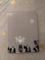 HUMANBIOLOGICS book cover. Features three men with their hands raised. They are standing in front of a nearly featureless grey wall with photographs and the seal of the united states on it.