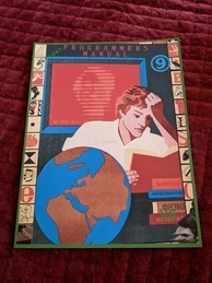 Cover of the 9front Programmer's Manual V6. Features a person intently reading a book while several more books are in a pile waiting to be read and a globe sits next to the reader. A red screen is behind the reader with the text 'up 2920 days' with the rest of the message obscured. The 9front logo is in the upper-right corner, and the indicator V6 is in the bottom-right.