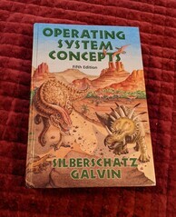 Cover of the Operating System Concepts book, fifth edition. Featuring a prehistoric landscape where several dinosaurs are featured that I will need to do some research to identify.